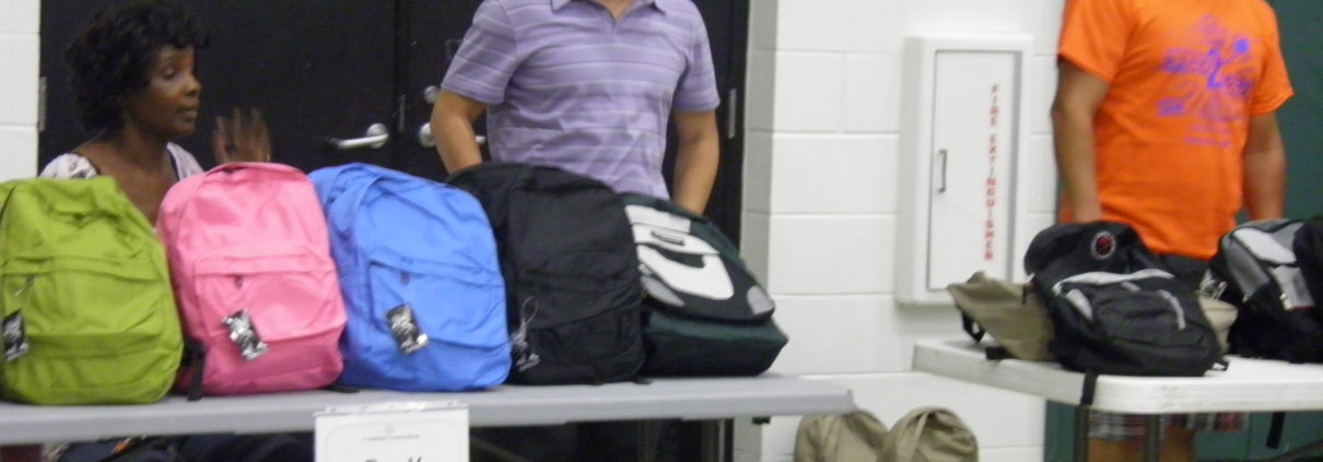 Backpacks on table with smiling volunteers